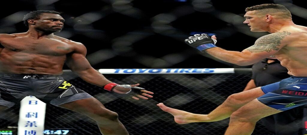 Two mixed martial arts fighters, one landing a kick, inside a cage