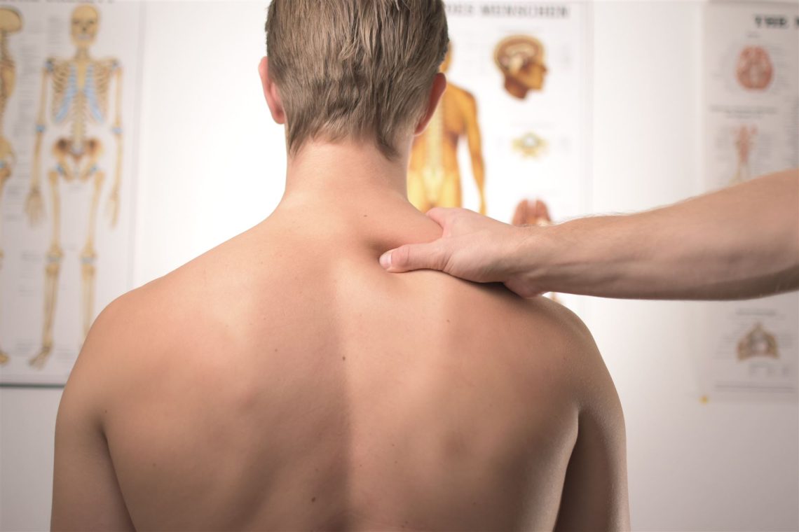 A therapist's hand resting on a patient's shoulder in a treatment room