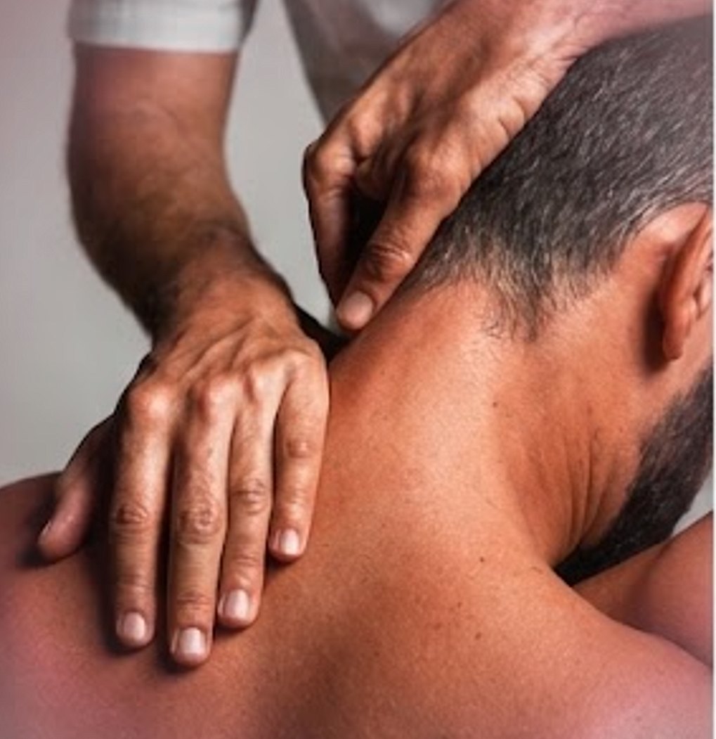 A therapist's hands releasing the muscles at the base of a patient's neck.