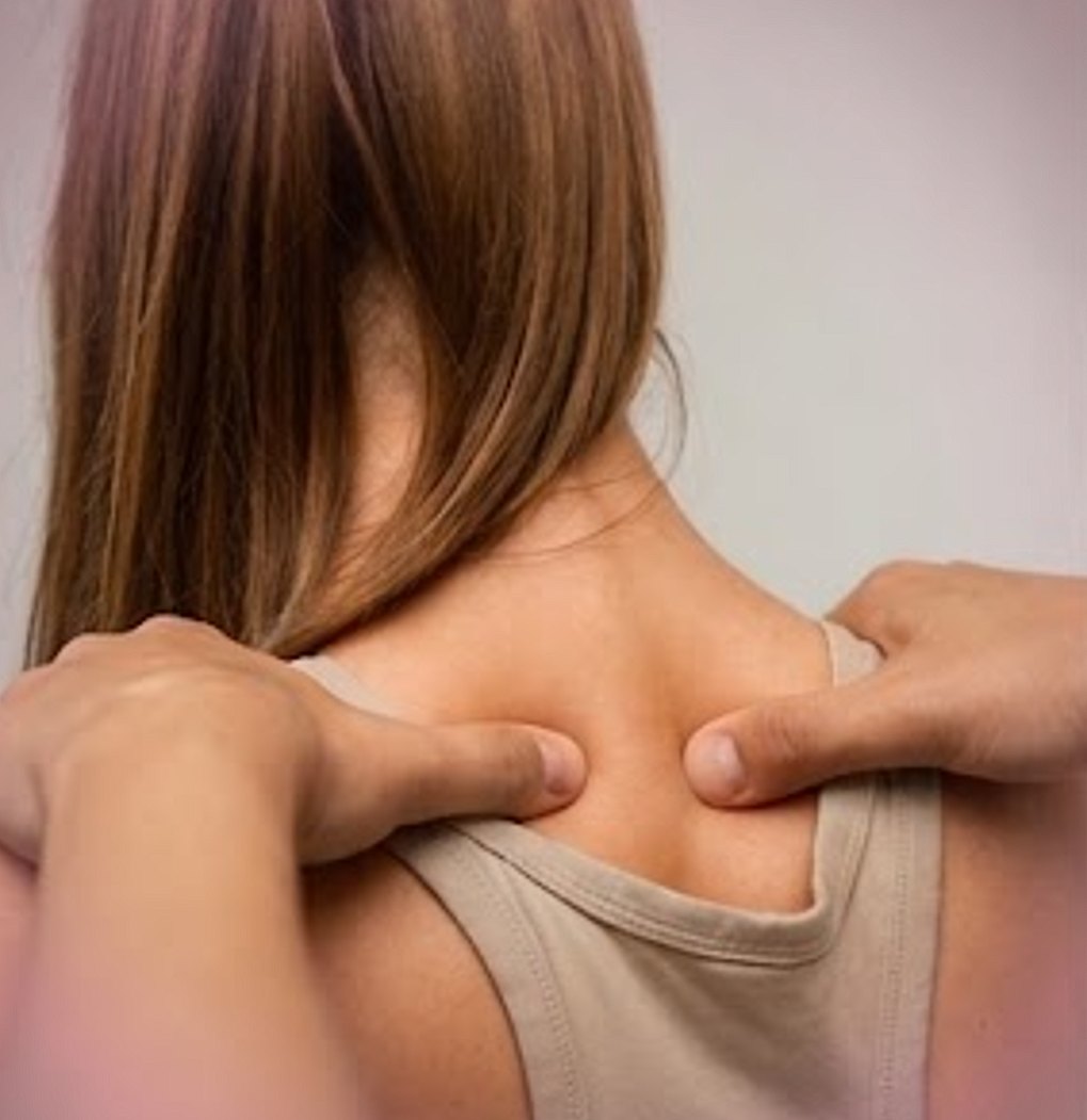 A therapist's hands working across the tops of a patient's shoulders.